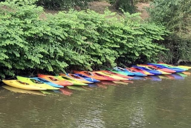 20 Kanus in unterschiedlichen Farben am Ufer der Fils