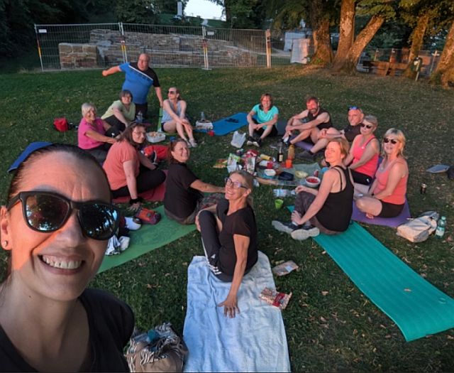 Teilnehmer der Pilates-Einheit sitzen im Kreis auf ihren Matten beim gemütlichen Beisammensein.