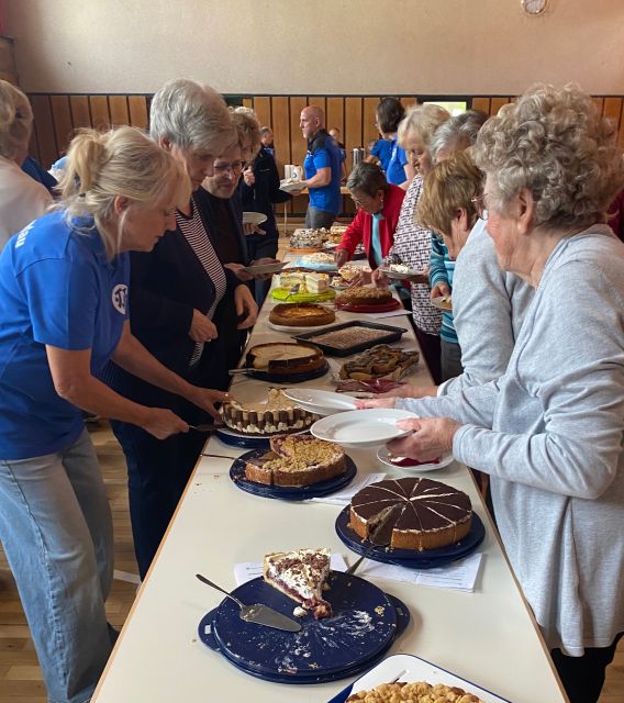 ca. 10 Personen, die sich am Kuchenbüffet bedienen